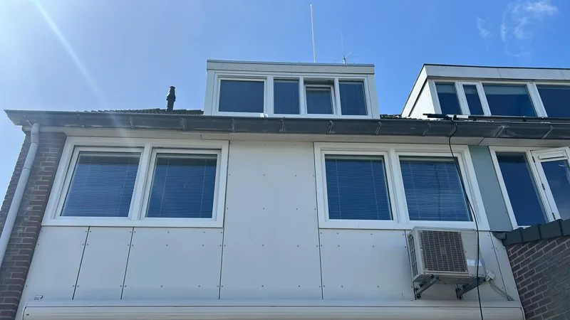 Brede witte dakkapel met kunststof kozijnen op een rijtjeshuis
