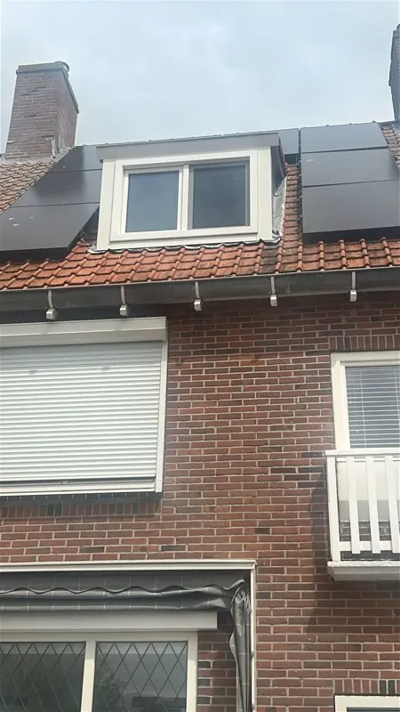 Witte dakkapel tussen zonnepanelen