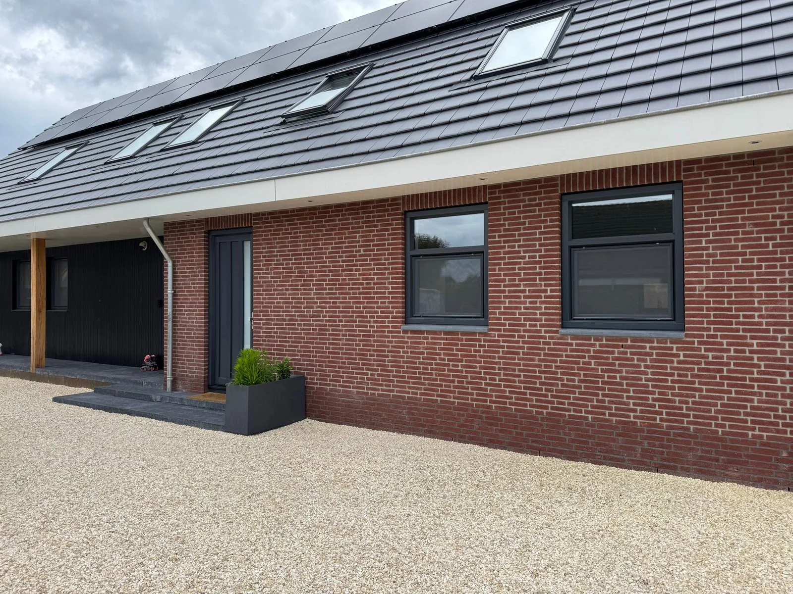 Rode bakstenen woning met antraciet kunststof kozijnen