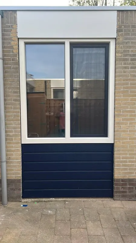 Donkerblauwe gevelplanken onder een raam