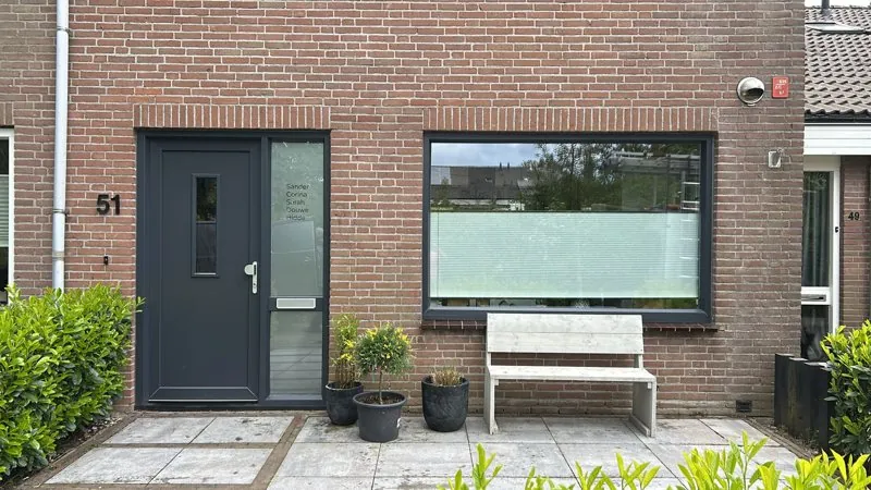 Antraciet voordeur en raam in een bakstenen gevel